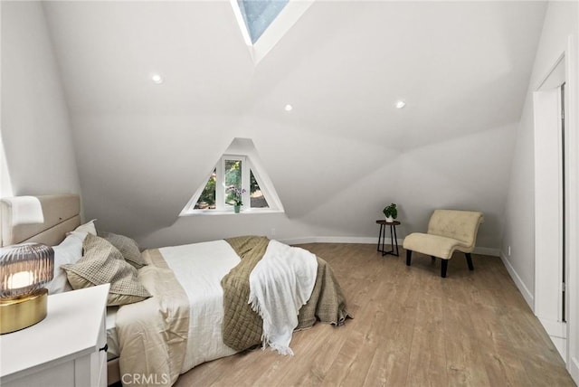 bedroom with light wood-type flooring and lofted ceiling with skylight