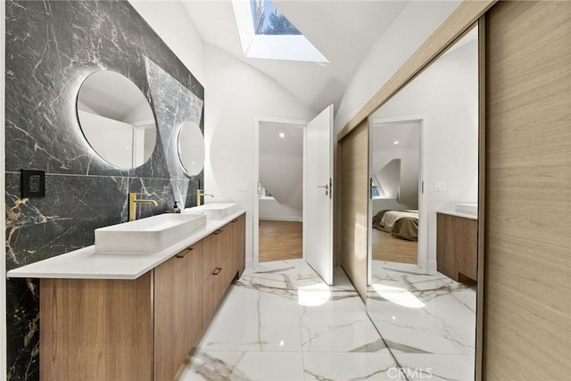 bathroom featuring vaulted ceiling with skylight, tile walls, and vanity