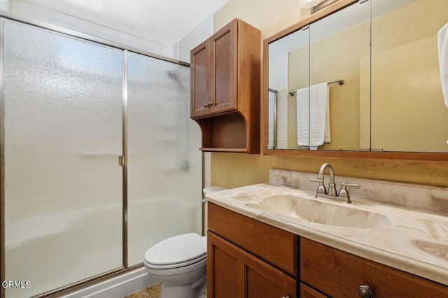 bathroom featuring toilet, vanity, and a shower with door