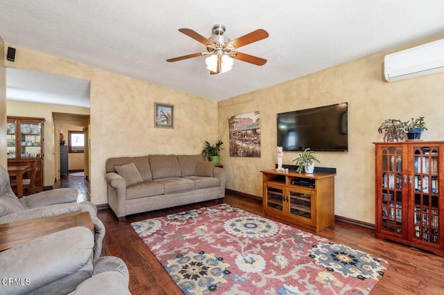 living room with hardwood / wood-style floors, a wall unit AC, and ceiling fan