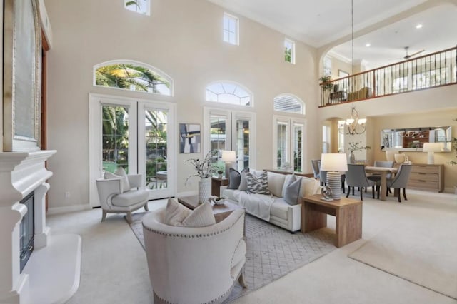 living room with a towering ceiling, ceiling fan with notable chandelier, light colored carpet, and french doors