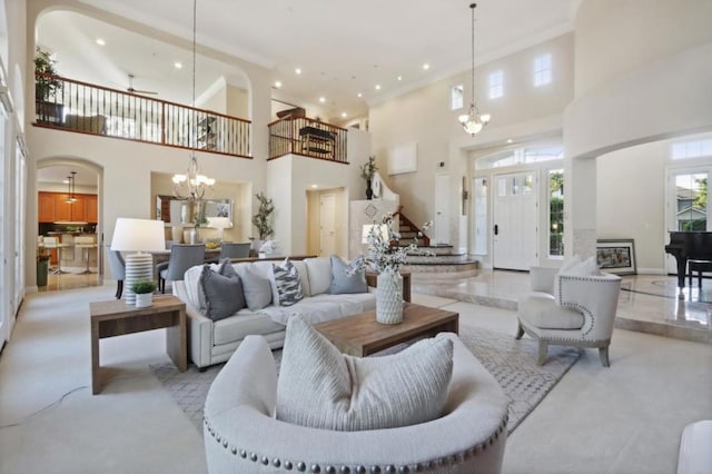 living room with a towering ceiling and ceiling fan with notable chandelier