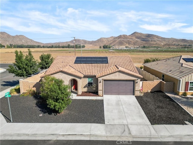 view of front facade with a mountain view, a garage, and solar panels