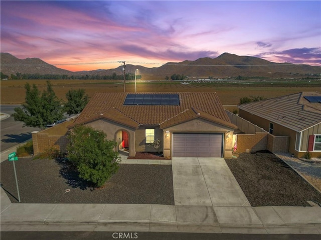 view of front facade with a garage, a mountain view, and solar panels