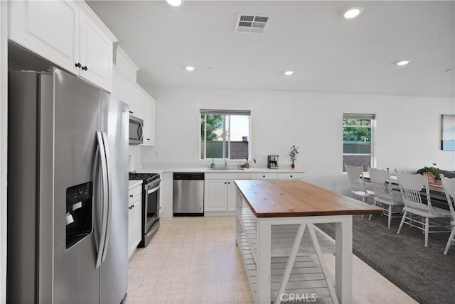 kitchen with white cabinetry, stainless steel appliances, sink, and light carpet