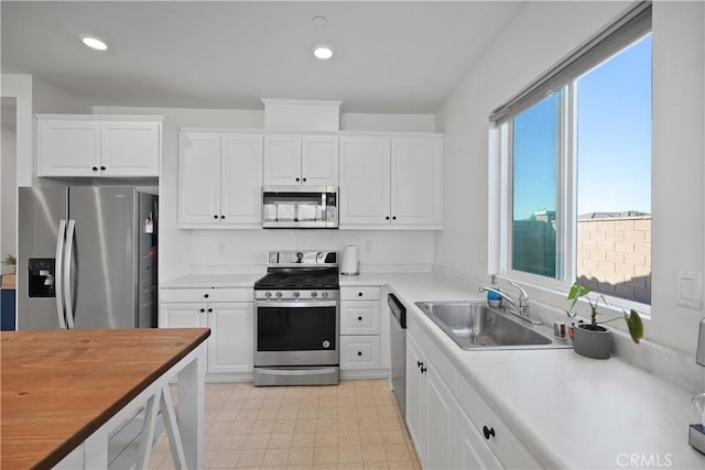 kitchen featuring wood counters, sink, stainless steel appliances, and white cabinets