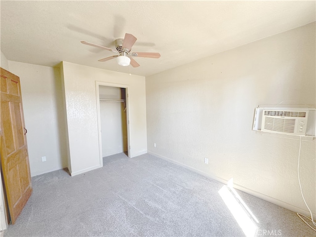 unfurnished bedroom featuring ceiling fan, light colored carpet, a closet, and a wall mounted air conditioner