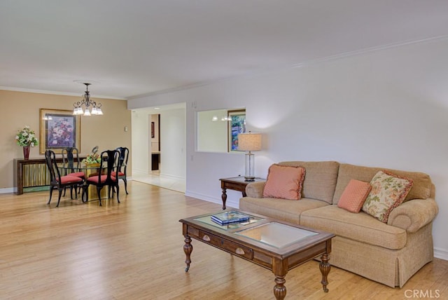 living room with crown molding, a notable chandelier, and light wood-type flooring