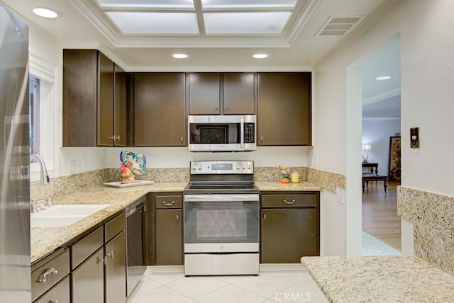 kitchen with ornamental molding, dark brown cabinets, light stone counters, and stainless steel appliances