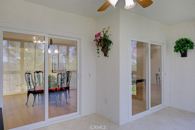 entryway with ceiling fan with notable chandelier, a textured ceiling, and tile patterned flooring