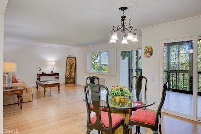 dining area featuring light wood-type flooring, a chandelier, and ornamental molding