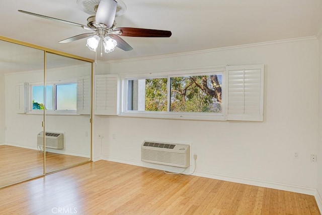 unfurnished bedroom with ceiling fan, multiple windows, an AC wall unit, and a closet