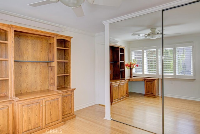 unfurnished office featuring built in desk, ceiling fan, and ornamental molding