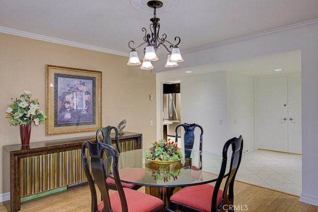 dining space with light wood-type flooring, an inviting chandelier, and ornamental molding