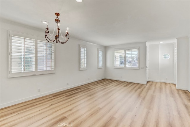 spare room featuring a notable chandelier, crown molding, and light hardwood / wood-style flooring