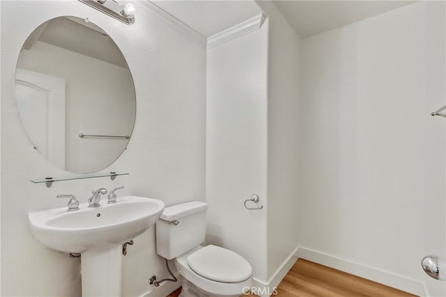 bathroom featuring crown molding, hardwood / wood-style flooring, and toilet