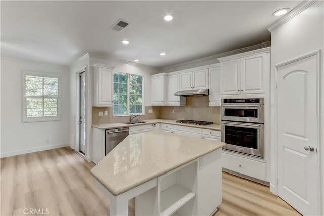 kitchen with white cabinets, stainless steel appliances, light wood-type flooring, and a kitchen island