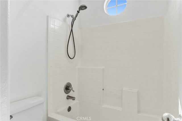 bathroom with toilet and tiled shower / bath combo