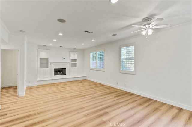 unfurnished living room with light wood-type flooring, crown molding, ceiling fan, and built in shelves