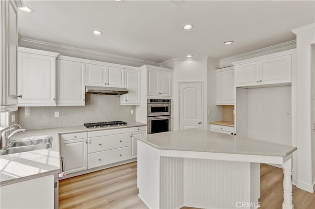 kitchen featuring stainless steel appliances, sink, a center island, and white cabinetry