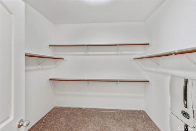 walk in closet with water heater and carpet