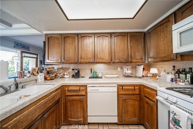 kitchen featuring sink, tasteful backsplash, a textured ceiling, white appliances, and light tile patterned flooring