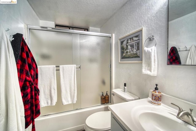 full bathroom with vanity, toilet, a textured ceiling, and combined bath / shower with glass door