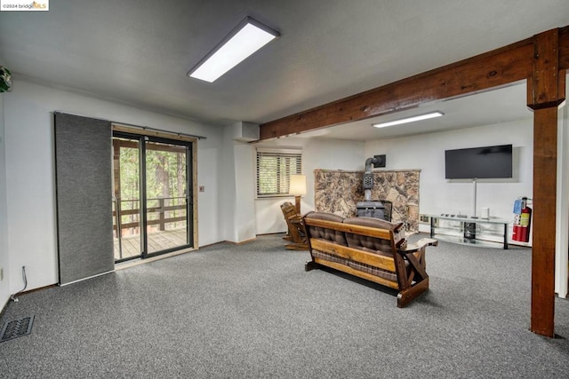 carpeted living room featuring a wood stove and beam ceiling