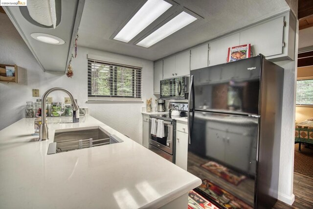 kitchen featuring black appliances, sink, dark wood-type flooring, and a wealth of natural light