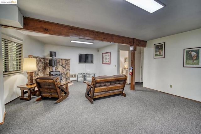 carpeted living room featuring beamed ceiling and a wood stove