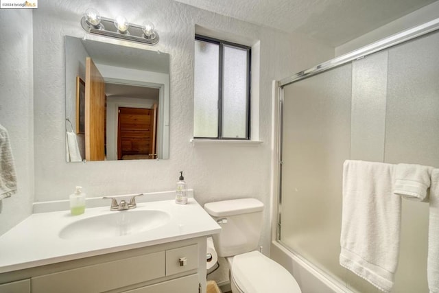 full bathroom with enclosed tub / shower combo, a textured ceiling, vanity, and toilet