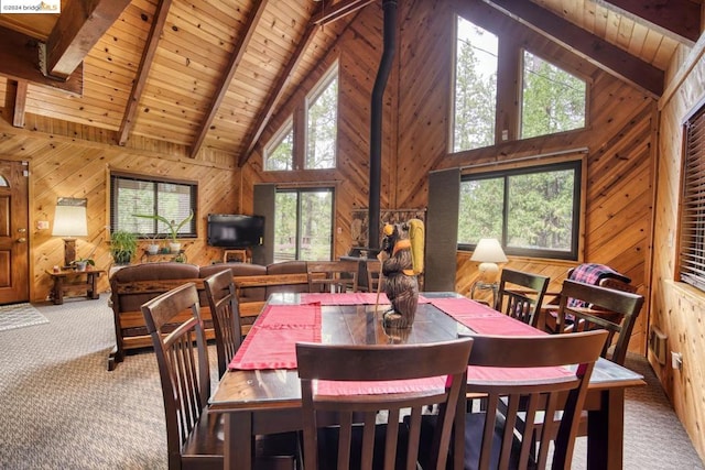 carpeted dining room featuring wooden walls, a wood stove, and a wealth of natural light