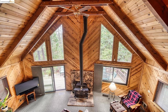 unfurnished living room featuring a wood stove, a wealth of natural light, and wooden ceiling