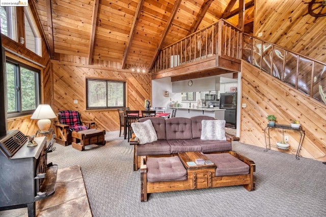 carpeted living room with beamed ceiling, plenty of natural light, wood walls, and wooden ceiling