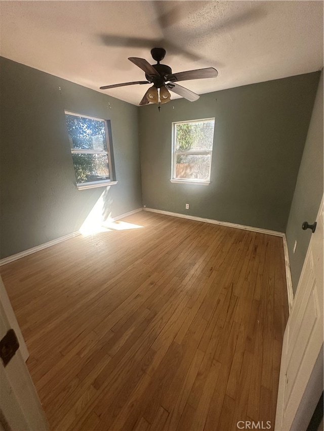 unfurnished room with wood-type flooring, ceiling fan, and a textured ceiling