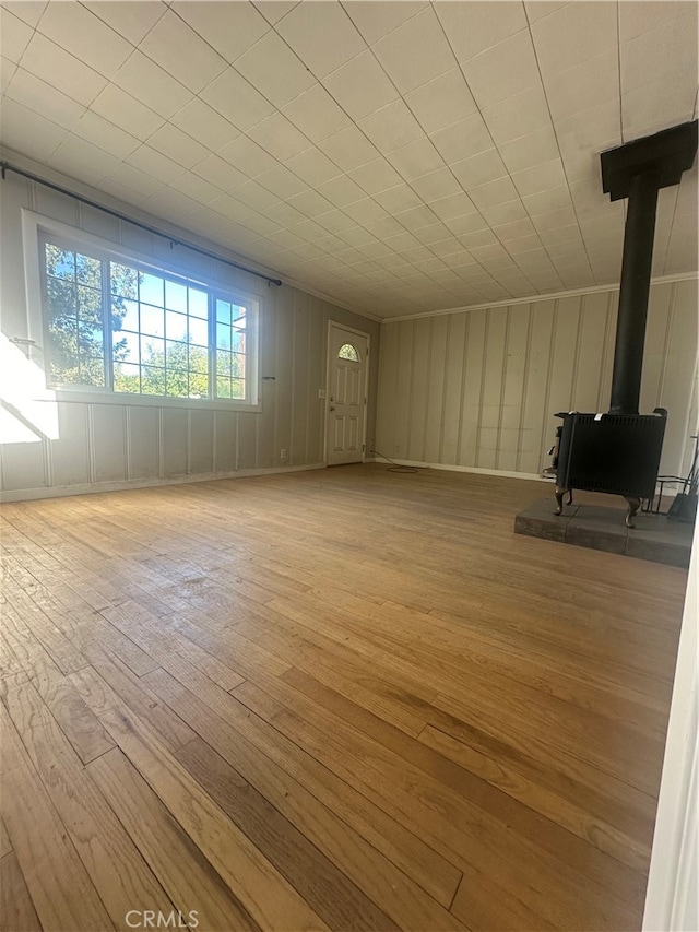 unfurnished living room featuring a wood stove and light hardwood / wood-style floors