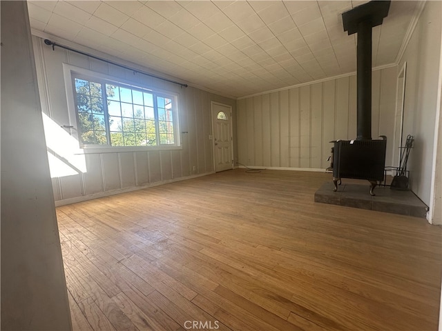 unfurnished living room featuring crown molding, light hardwood / wood-style floors, and a wood stove