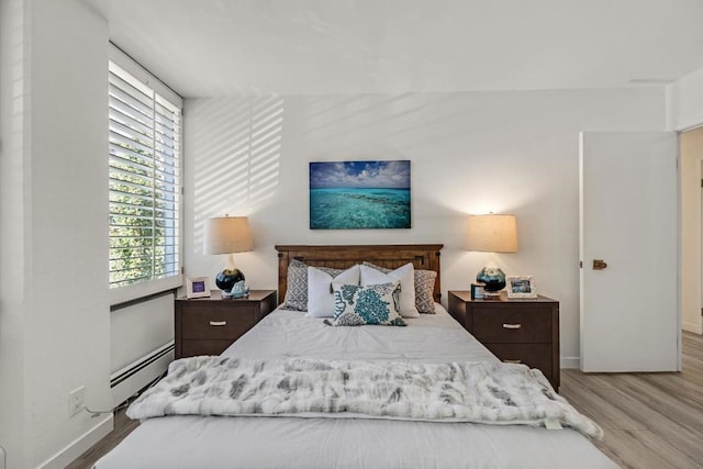 bedroom featuring baseboard heating and light hardwood / wood-style floors