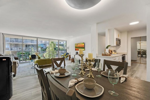 dining area featuring a wall of windows and light hardwood / wood-style floors