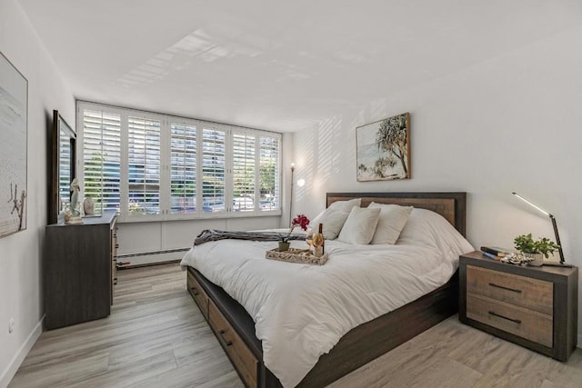 bedroom featuring a baseboard heating unit and light hardwood / wood-style floors