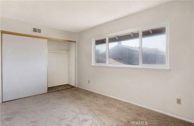 unfurnished bedroom with a closet, light carpet, and a textured ceiling