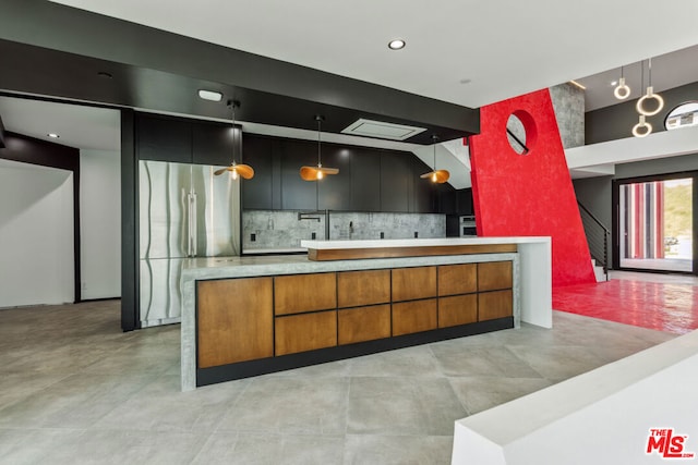 kitchen with stainless steel fridge, tasteful backsplash, and hanging light fixtures