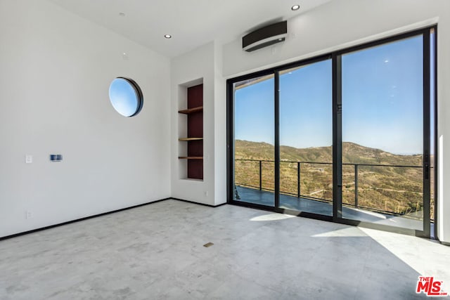 spare room featuring a mountain view and built in shelves