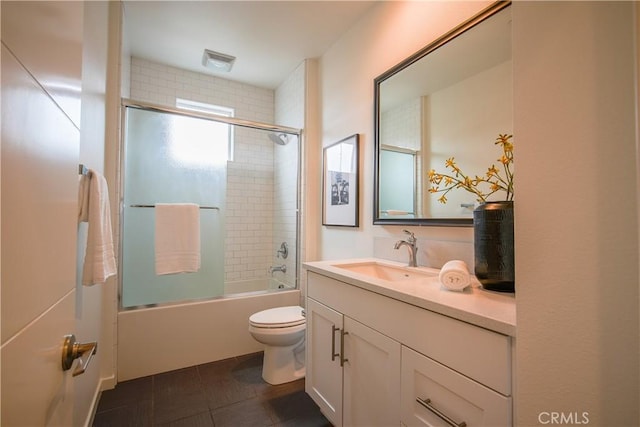 full bathroom featuring tile patterned flooring, vanity, toilet, and bath / shower combo with glass door