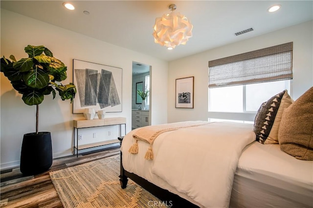 bedroom with hardwood / wood-style floors and ensuite bathroom