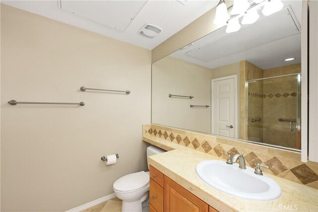 bathroom featuring vanity, backsplash, toilet, and a shower with shower door