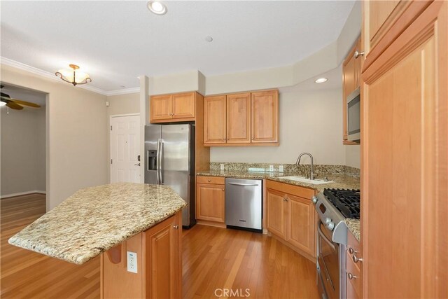 kitchen featuring ceiling fan, sink, a center island, light hardwood / wood-style flooring, and appliances with stainless steel finishes