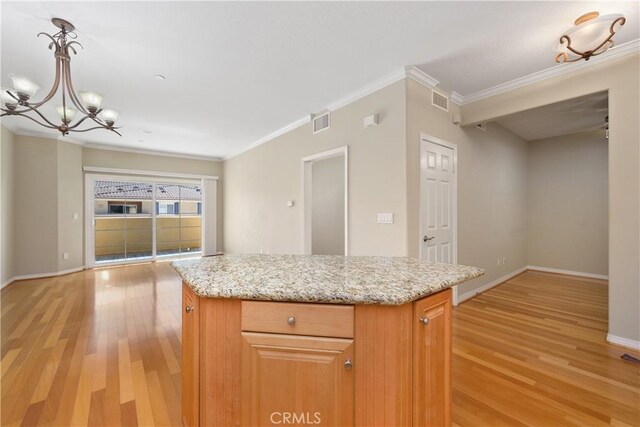 kitchen featuring a center island, crown molding, hanging light fixtures, and light hardwood / wood-style flooring