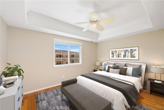 bedroom with a tray ceiling, ceiling fan, and hardwood / wood-style floors