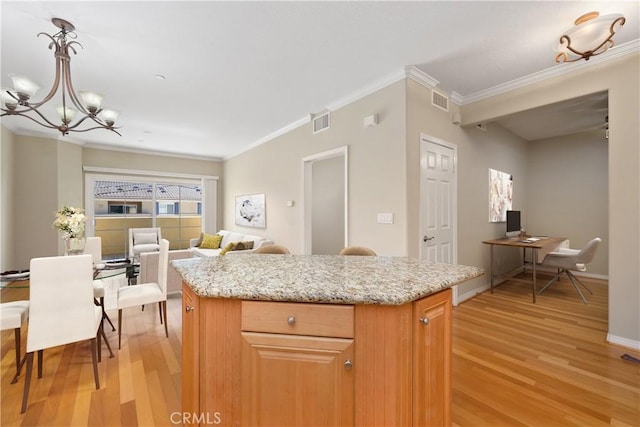 kitchen featuring pendant lighting, a center island, light wood-type flooring, and crown molding